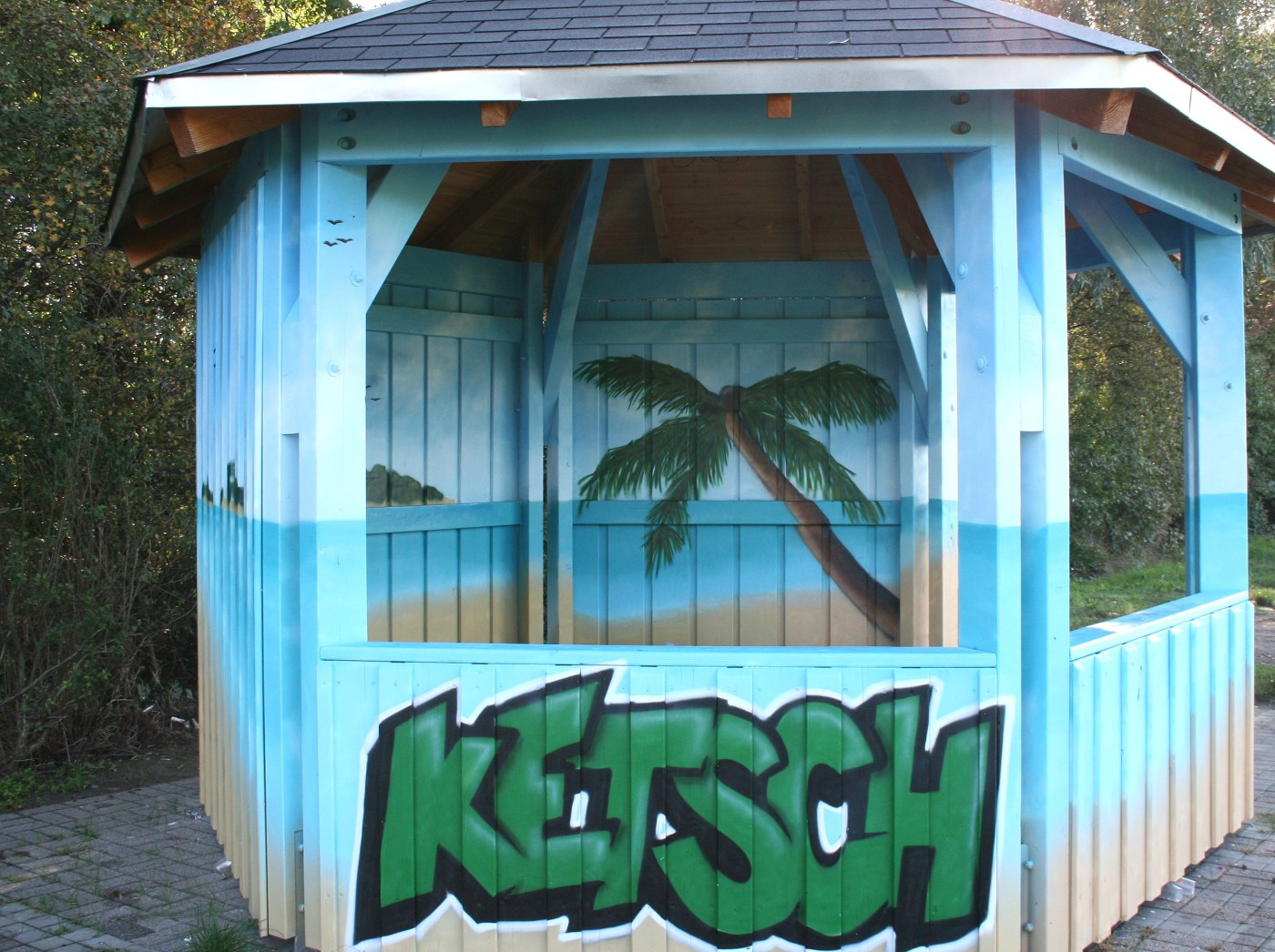 Holzpavillon mit Palmen-Graffiti und Schriftzug Ketsch