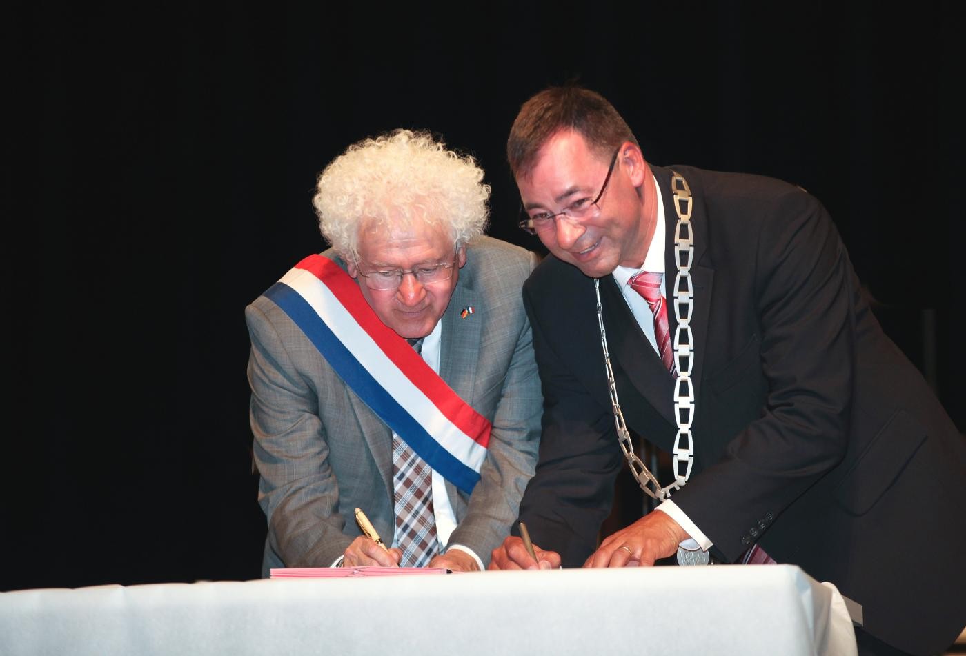 Das Bild zeigt die Bürgermeister Goua und Kappenstein beim Unterschreiben ihrer erneuten Freundschaftsbekundung